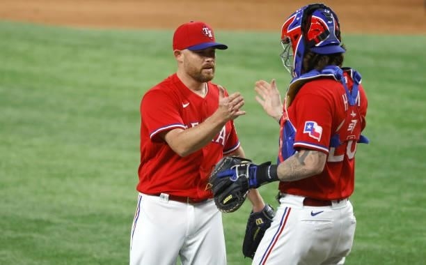 Ian Kennedy of the Texas Rangers and teammate Jonah Heim celebrate the teams 3-2 win over the Oakland Athletics at Globe Life Field on July 9, 2021...