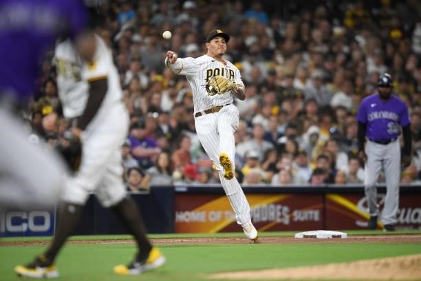 Manny Machado of the San Diego Padres throws to first base but fails to get the out on a single by Chris Owings of the Colorado Rockies during the...
