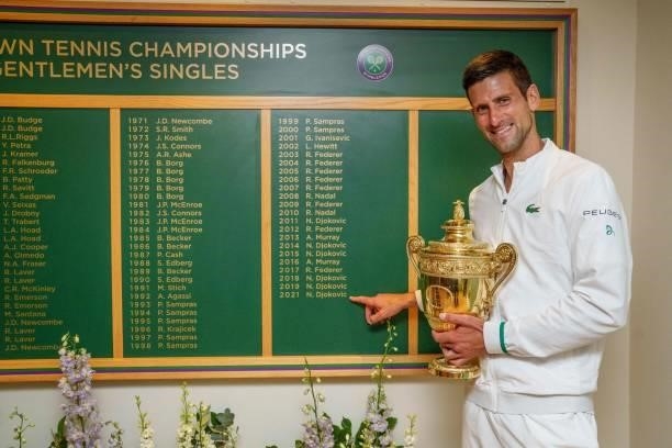 Serbia's Novak Djokovic holds the winner's trophy in front of the honours board and points to his name after defeating Italy's Matteo Berrettini...