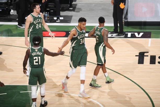 Giannis Antetokounmpo of the Milwaukee Bucks high-fives teammate Jrue Holiday during the game against the Phoenix Suns during Game Three of the 2021...