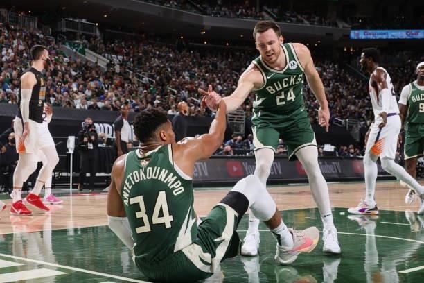 Pat Connaughton helps up Giannis Antetokounmpo of the Milwaukee Bucks during Game Three of the 2021 NBA Finals on July 11, 2021 at the Fiserv Forum...
