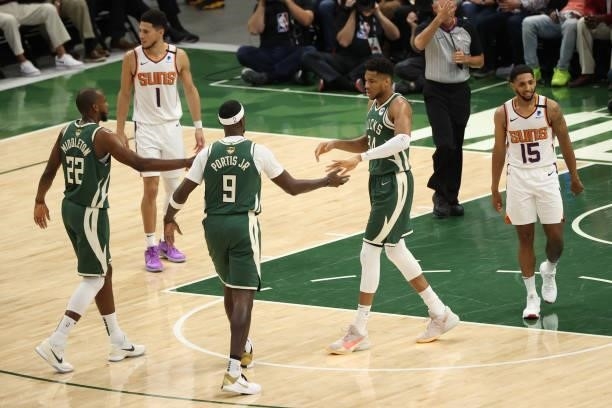 Khris Middleton, Bobby Portis, and Giannis Antetokounmpo of the Milwaukee Bucks hi-five during the game against the Phoenix Suns during Game Three of...