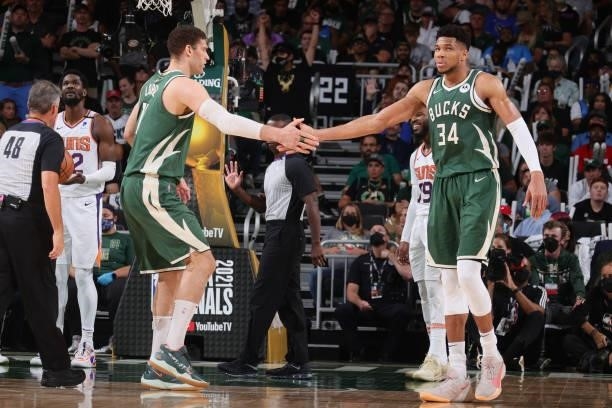 Brook Lopez hi-fives Giannis Antetokounmpo of the Milwaukee Bucks during Game Three of the 2021 NBA Finals on July 11, 2021 at the Fiserv Forum...