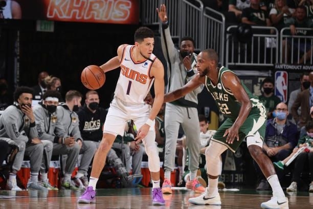 Khris Middleton of the Milwaukee Bucks plays defense on Devin Booker of the Phoenix Suns during Game Three of the 2021 NBA Finals on July 11, 2021 at...