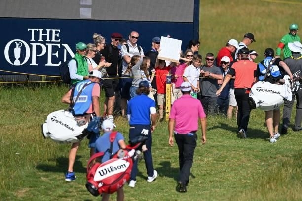 Young boy in the crowd holds up a sign asking for someone to play "rock, paper, scissors for a golf ball