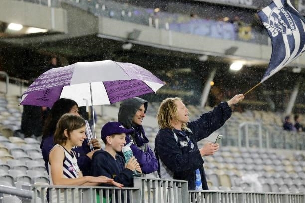 Footie fans look on in the rain during the 2021 AFL Round 18 match between the Fremantle Dockers and the Geelong Cats at Optus Stadium on July 15,...