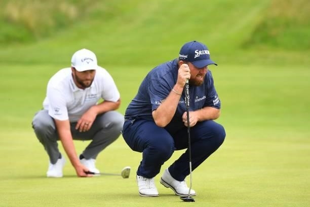 Ireland's Shane Lowry and Spain's Jon Rahm line up their putts on the 8th green during their first round on day one of The 149th British Open Golf...