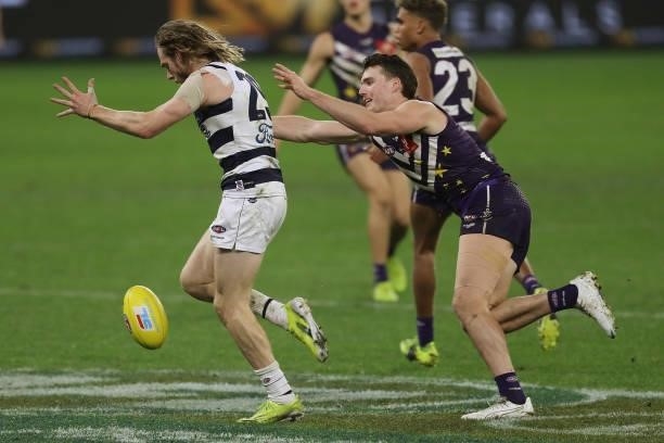 Cameron Guthrie of the Cats kicks the ball under pressure from Blake Acres of the Dockers during the 2021 AFL Round 18 match between the Fremantle...