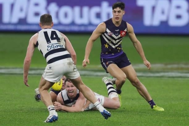 Patrick Dangerfield of the Cats handpasses the ball as he is tackled by Caleb Serong of the Dockers during the 2021 AFL Round 18 match between the...