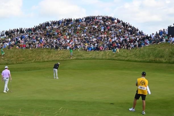 Spectators watch as US golfer Rickie Fowler putts on the 6th green during his first round on day one of The 149th British Open Golf Championship at...