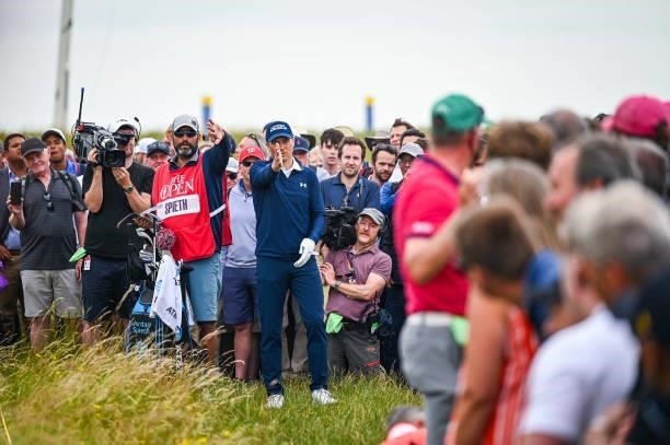 Jordan Spieth and his caddie Michael Greller gesture for fans to move to play a shot from the rough on the 14th hole during Day One of the 149th The...