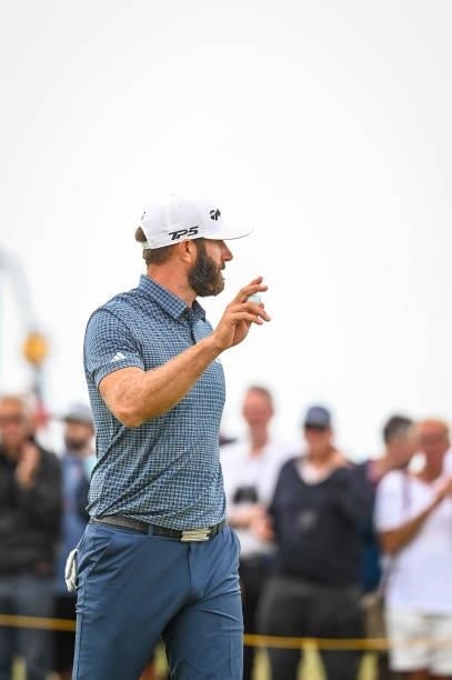 Dustin Johnson waves his ball to fans after making a birdie putt on the 15th hole green during Day One of the 149th The Open Championship at Royal...