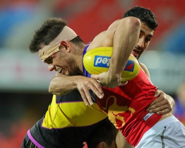 Brandon Starcevich is tackled during the 2021 AFL Round 18 match between the Richmond Tigers and the Brisbane Lions at Metricon Stadium on July 16,...