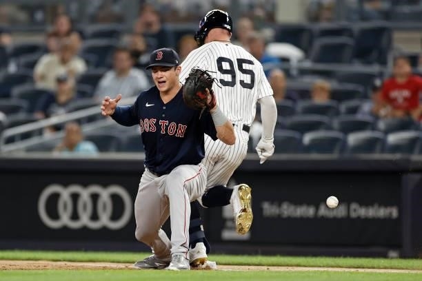 Bobby Dalbec of the Boston Red Sox reacts as he is unable to handle the throw and Trey Amburgey of the New York Yankees is safe at first base during...