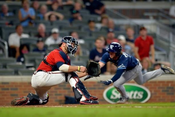 Brett Phillips of the Tampa Bay Rays beats the throw to home plate guarded by Kevan Smith of the Atlanta Braves in the tenth inning at Truist Park on...