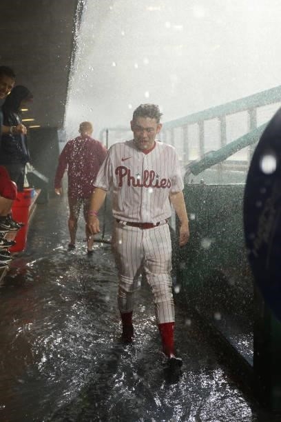 Philadelphia Phillies bat boy walks through ankle deep water in the dugout during a thunder storm that intruded play during the tenth inning of a...