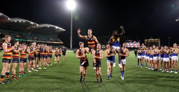 Brodie Smith of the Crows and Nic Naitanui of the Eagles get chaired off in their 200th games during the 2021 AFL Round 18 match between the Adelaide...