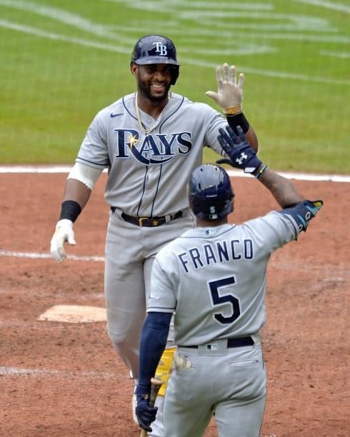 Yandy Diaz of the Tampa Bay Rays high fives Wander Franco after hitting a two-run home run in the seventh inning against the Atlanta Braves at Truist...