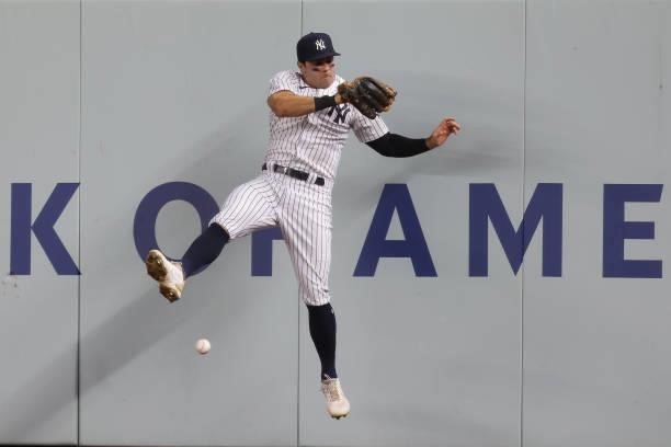 Right fielder Trey Amburgey of the New York Yankees crashes into the wall going for a ball off the bat of Christian Vázquez of the Boston Red Sox...