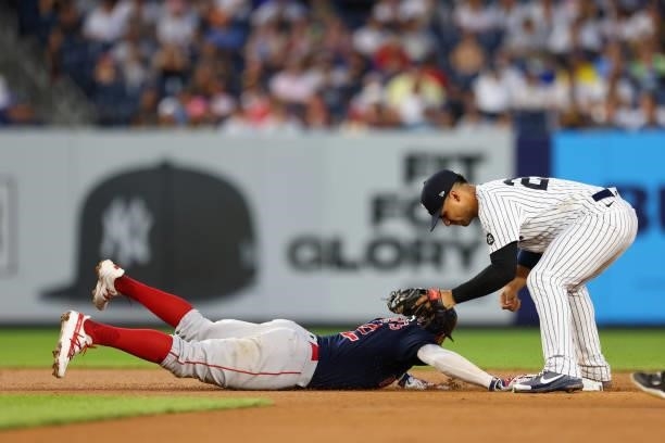 Xander Bogaerts of the Boston Red Sox dives back into second base ahead of the tag by shortstop Gleyber Torres of the New York Yankees on a pick-off...