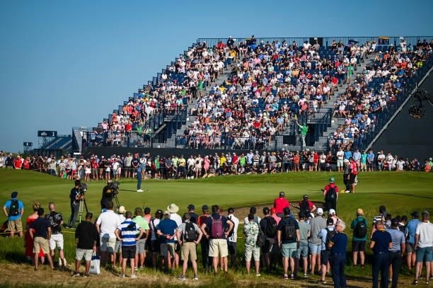 Fans watch Collin Morikawa putt on the 17th hole green from a grandstand during Day Four of the 149th The Open Championship at Royal St. Georges Golf...