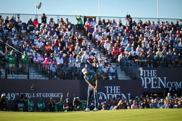 Collin Morikawa putts on the 18th hole green as fans watch from the grandstand during Day Four of the 149th The Open Championship at Royal St....
