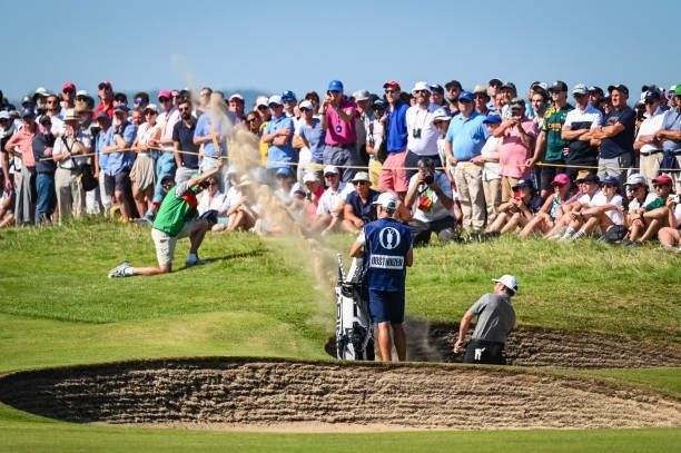 Louis Oosthuizen of South Africa plays his third shot from a bunker on the seventh hole as fans watch during Day Four of the 149th The Open...
