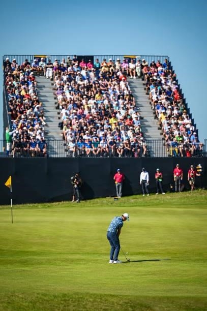Collin Morikawa chips a shot to the seventh hole green as fans watch from a grandstand during Day Four of the 149th The Open Championship at Royal...