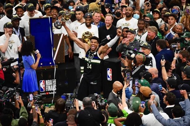 Giannis Antetokounmpo of the Milwaukee Bucks celebrates while holding the Bill Russell NBA Finals Most Valuable Player Award after the game against...