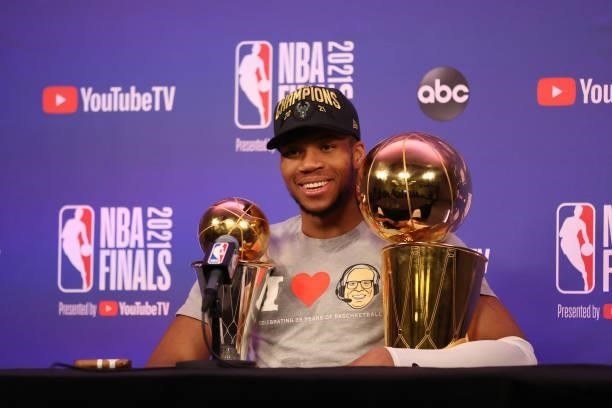 Giannis Antetokounmpo of the Milwaukee Bucks talks to the media with the Larry O'Brien Trophy and the Bill Russell Finals MVP Award after winning the...
