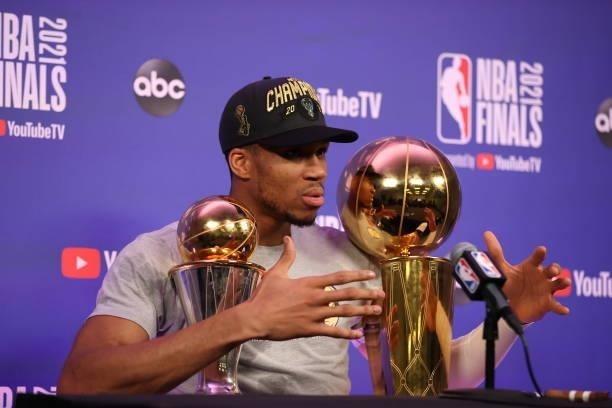 Giannis Antetokounmpo of the Milwaukee Bucks talks to the media with the Larry O'Brien Trophy and the Bill Russell Finals MVP Award after winning the...