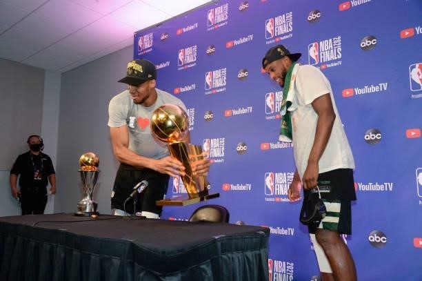 Giannis Antetokounmpo of the Milwaukee Bucks and Khris Middleton of the Milwaukee Bucks sit with the Bill Russell NBA Finals MVP Award and Larry...