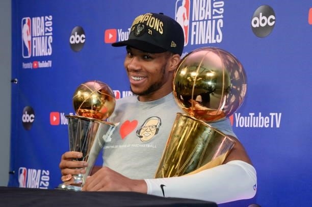 Giannis Antetokounmpo of the Milwaukee Bucks sits with the Bill Russell NBA Finals MVP Award and Larry O'Brien Trophy as he talks to the media after...