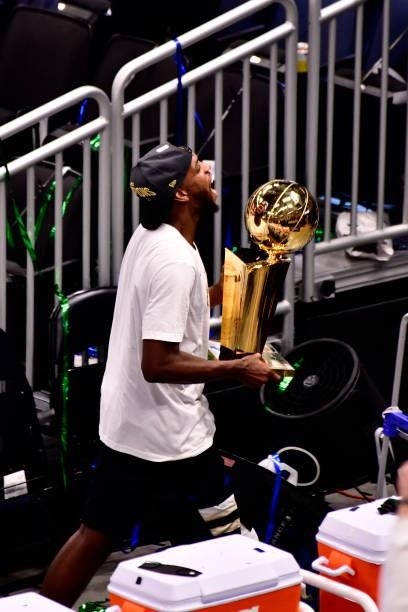Khris Middleton of the Milwaukee Bucks celebrates with the Larry O'Brien Trophy after winning Game Six of the 2021 NBA Finals against the Phoenix...