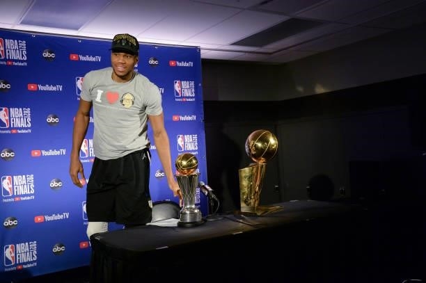 Giannis Antetokounmpo of the Milwaukee Bucks holds the Bill Russell NBA Finals MVP Award and Larry O'Brien Trophy as he talks to the media after...