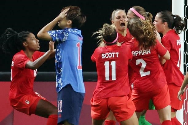 Canada's players celebrate goalkeeper Stephanie Labbe's save as Japan's forward Mina Tanaka reacts to missing a penalty shot during the Tokyo 2020...