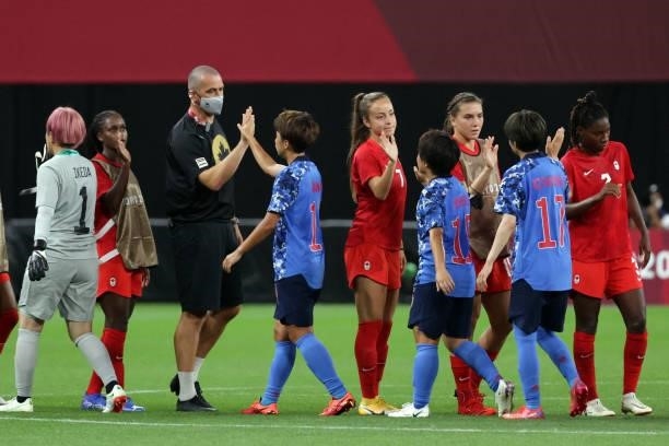 Both teams slap hands at the end of the Tokyo 2020 Olympic Games women's group E first round football match between Japan and Canada at the Sapporo...