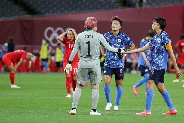 Japan's defender Saki Kumagai slaps hands with Japan's goalkeeper Sakiko Ikeda at the end of the Tokyo 2020 Olympic Games women's group E first round...