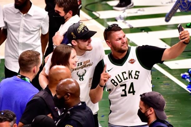 Pat Connaughton of the Milwaukee Bucks takes a selfie with fans after winning Game Six of the 2021 NBA Finals against the Phoenix Suns on July 20,...