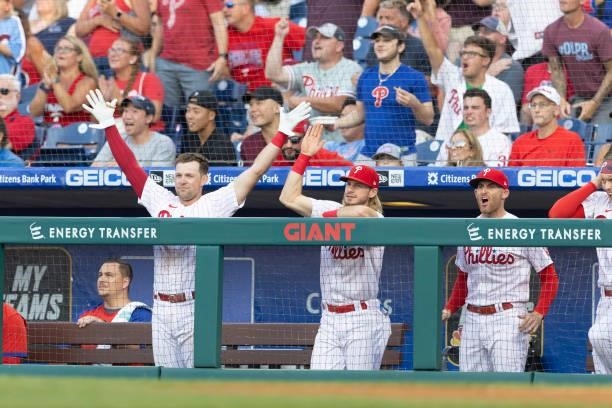 Rhys Hoskins, Travis Jankowski, and Brad Miller of the Philadelphia Phillies react after a solo home run by J.T. Realmuto in the bottom of the first...
