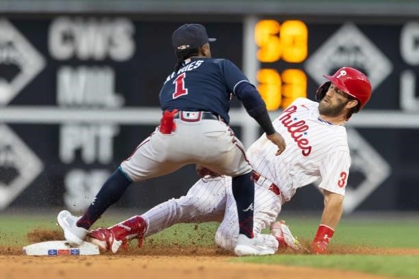 Bryce Harper of the Philadelphia Phillies slides in safely for a double past the tag of Ozzie Albies of the Atlanta Braves in the bottom of the third...