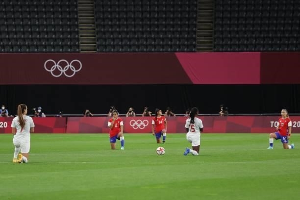 Players take a knee for the fight against racism before the Tokyo 2020 Olympic Games women's group E first round football match between Chile and...