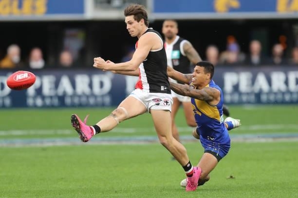 Jack Steele of the Saints kicks the ball under pressure from Tim Kelly of the Eagles during the 2021 AFL Round 19 match between the West Coast Eagles...