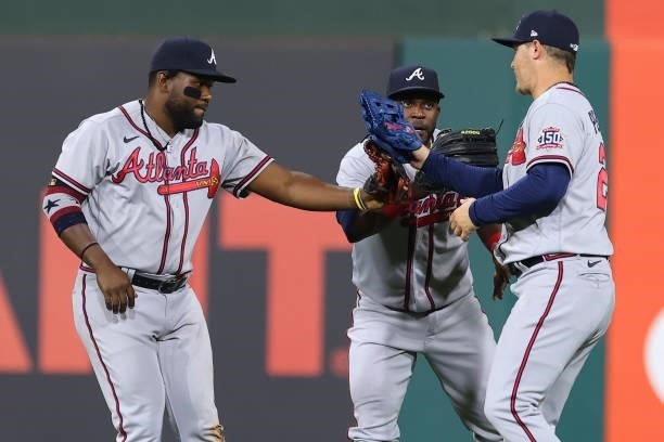 Outfielders Abraham Almonte, Guillermo Heredia and Joc Pederson of the Atlanta Braves slap gloves after defeating the Philadelphia Phillies 15-3 in a...