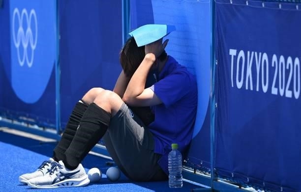 Ball boy covers his head under the heat during the women's pool B match of the Tokyo 2020 Olympic Games field hockey competition between New Zealand...