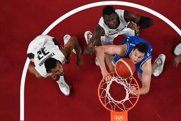 Germany's Johannes Thiemann and Isaac Bonga watch the basket in the men's preliminary round group B basketball match between Germany and Italy during...