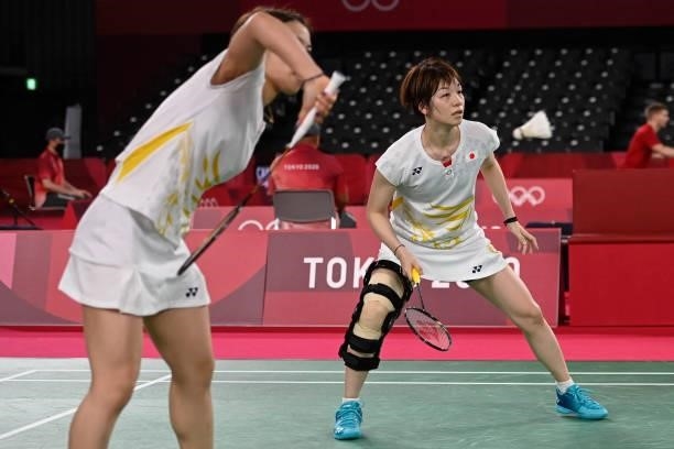 Japan's Yuki Fukushima hits a shot next to Japan's Sayaka Hirota in their women's doubles badminton group stage match against Malaysia's Chow Mei...