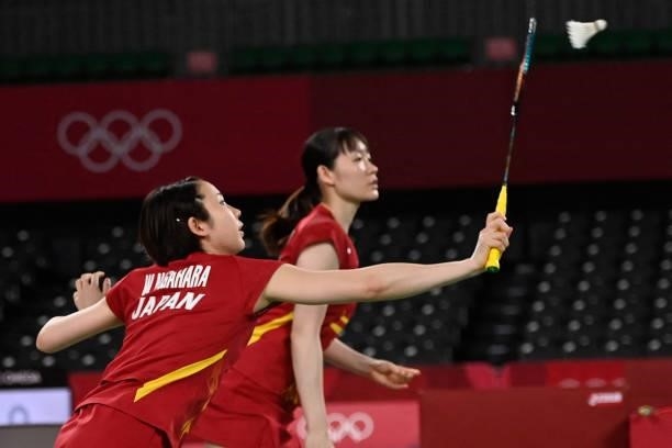 Japan's Wakana Nagahara hits a shot next to Japan's Mayu Matsumoto in their women's doubles badminton group stage match against Canada's Kristen Tsai...