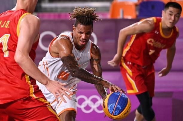 Netherlands' Jessey Voorn dribbles the ball past China's Hu Jinqiu and China's Gao Shiyan during the men's first round 3x3 basketball match between...