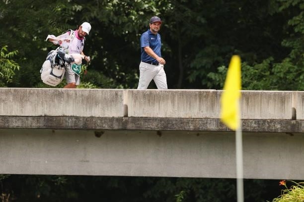 Roberto Diaz of Mexico looks on with his caddie as they walk across a bridge to the 8th green during the final round of the Price Cutter Charity...